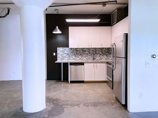 A kitchen with a white fridge and black and white tiled backsplash.