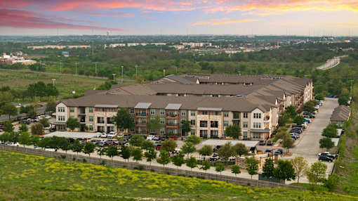 A large building complex with a parking lot in front of it.