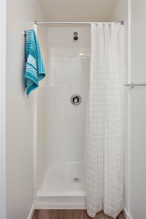 a bathroom with a white shower curtain and a blue towel