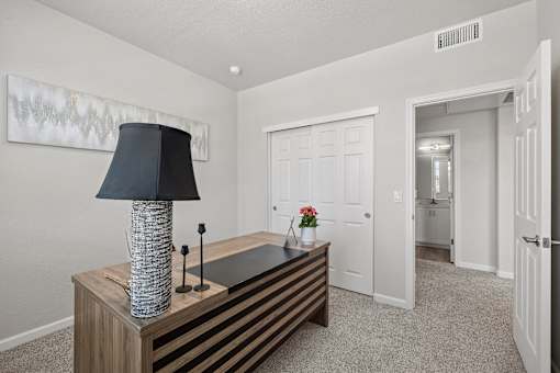 A room with a table, lamp, and painting on the wall.