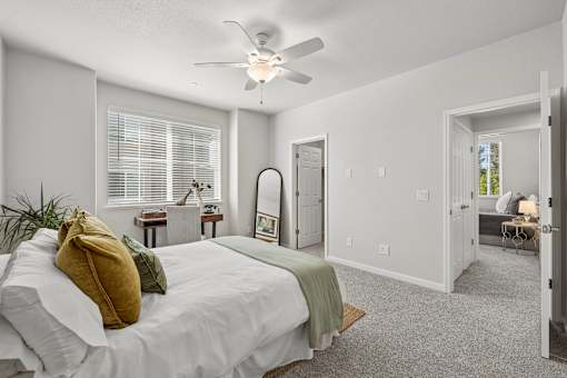 A bedroom with a bed, a mirror, and a ceiling fan.