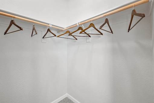 A row of hangers are lined up on a rail.