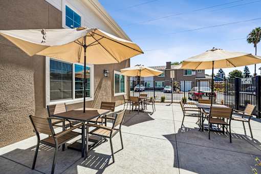 A patio with tables and chairs under umbrellas.