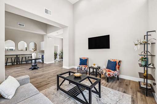A living room with a grey couch, a coffee table, and a TV on the wall.