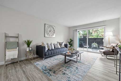 A living room with a grey sofa, a grey armchair, a grey rug, a grey floor, a grey wall, a grey floor lamp, a grey floor lamp, a grey floor lamp, a grey floor lamp, a grey floor