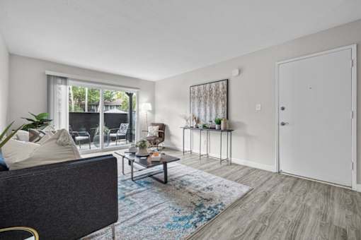 A living room with a grey couch, a coffee table, and a large window.
