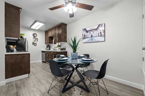 A dining room with a table set for two and a ceiling fan.