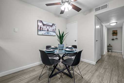 A dining room with a table set for two and a ceiling fan.