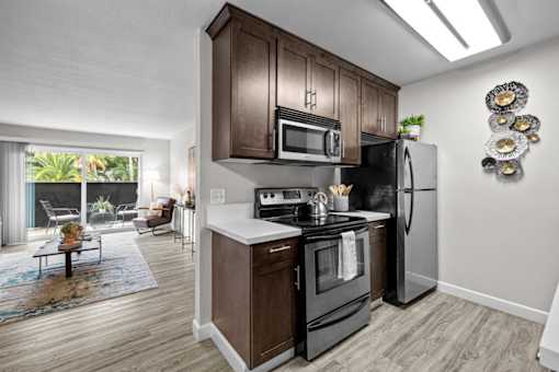 A modern kitchen with dark wood cabinets and stainless steel appliances.