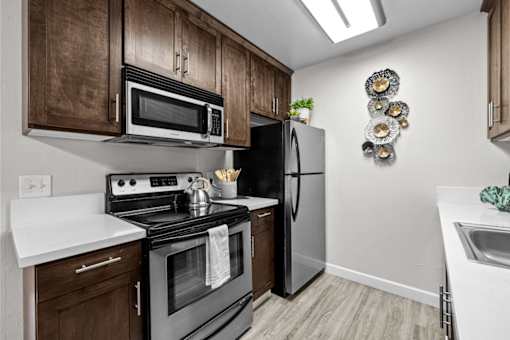 A kitchen with a black refrigerator, black oven, and black microwave.