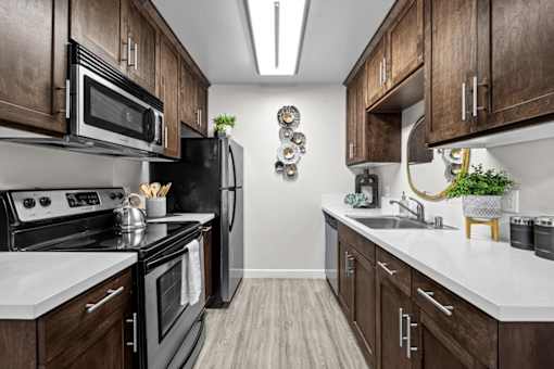 A kitchen with dark wood cabinets and white countertops.