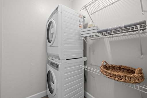 A white washing machine is stacked on top of another in a laundry room.