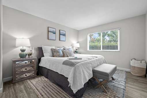 A bedroom with a bed, nightstand, and window.