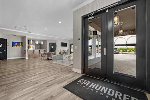 The interior of a building with a black door and a black mat that reads "HUNDRED ARTMENT".