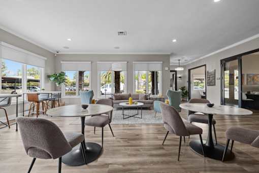 A modern dining room with a glass table surrounded by grey chairs.