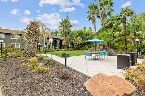A patio area with a table and chairs surrounded by a garden.