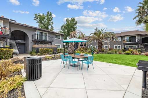 A patio with a table and chairs is surrounded by apartment buildings.