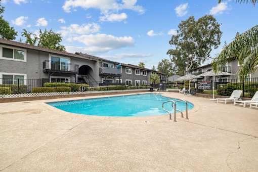 A swimming pool in a residential area with houses and trees in the background.