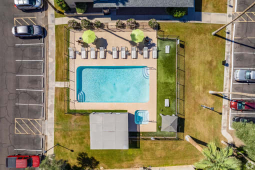 an aerial view of a swimming pool in a park with a fence
