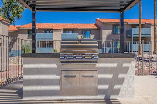 A bbq grill is in the middle of a concrete area.
