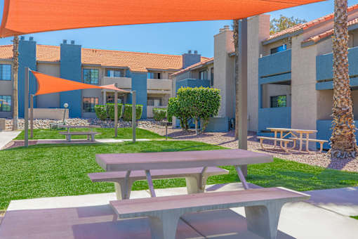 A picnic table is in the foreground of a sunny courtyard.