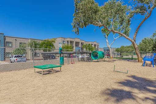 A playground with a green bench and a blue slide in front of a building.
