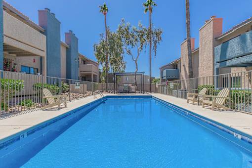 A swimming pool surrounded by palm trees and buildings.