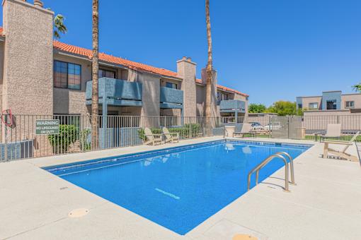 A swimming pool in front of a building with a warning sign.