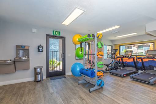 A gym with a variety of equipment including treadmills, exercise balls, and resistance bands.
