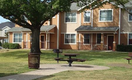 a picnic table in a park in front of an apartment building