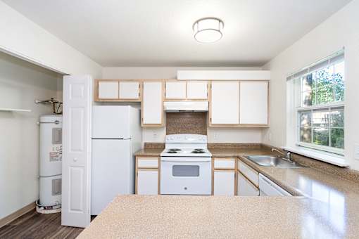 A kitchen with white appliances and wooden cabinets.
