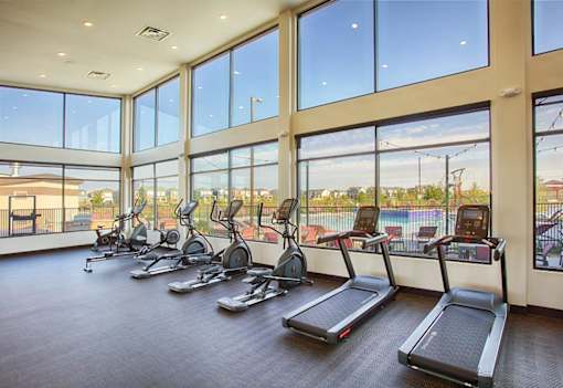A gym with treadmills and a view of a pool outside.