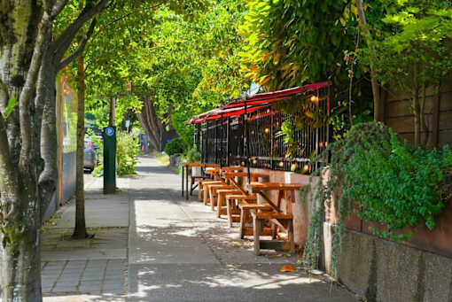 A row of wooden tables are lined up under a red awning.