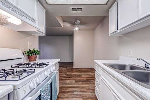 A kitchen with a white stove and a white sink.