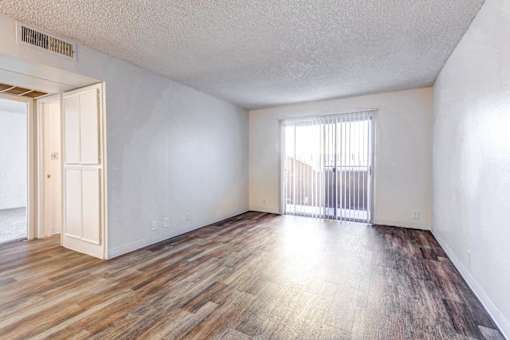 A room with wooden flooring and a window with blinds.