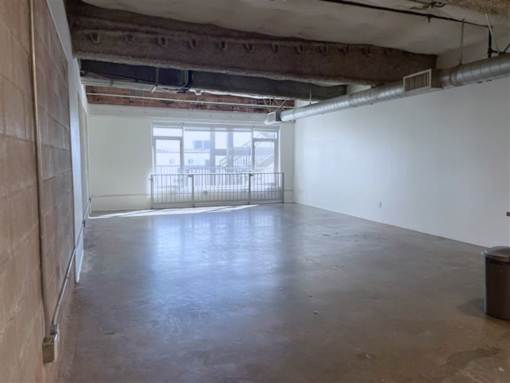 A large empty room with a window and a balcony.