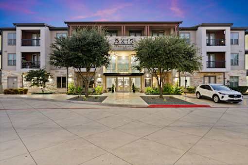A white car is parked in front of a building named Axis.