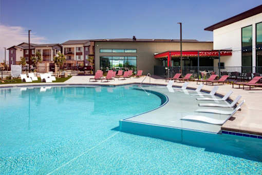 Pool with white lounge chairs in the water.