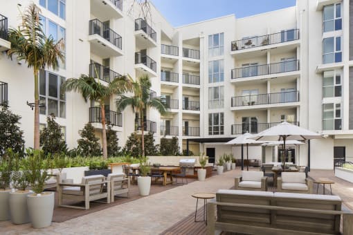 Hollywood CA Apartments - The Fifty Five Fifty - An Outdoor Courtyard At The Base Of The Building With Multiple Lounge Areas, A BBQ Area, And Beautiful Landscaping