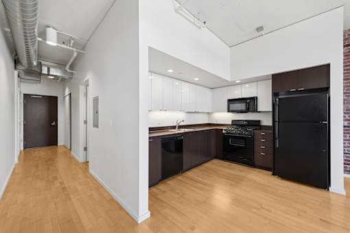 A kitchen with black appliances and wooden floors.