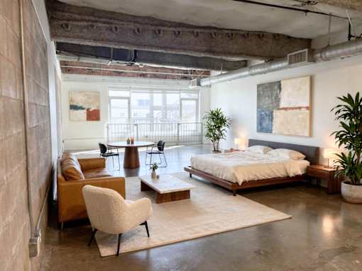 A bedroom with a bed, chair, and a table.