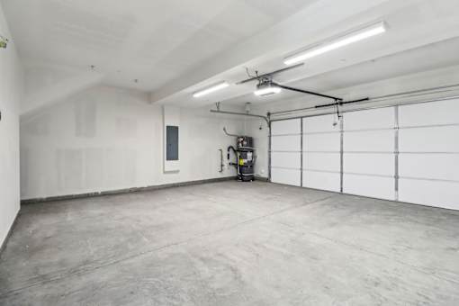 A large, empty garage with a concrete floor and white walls.
