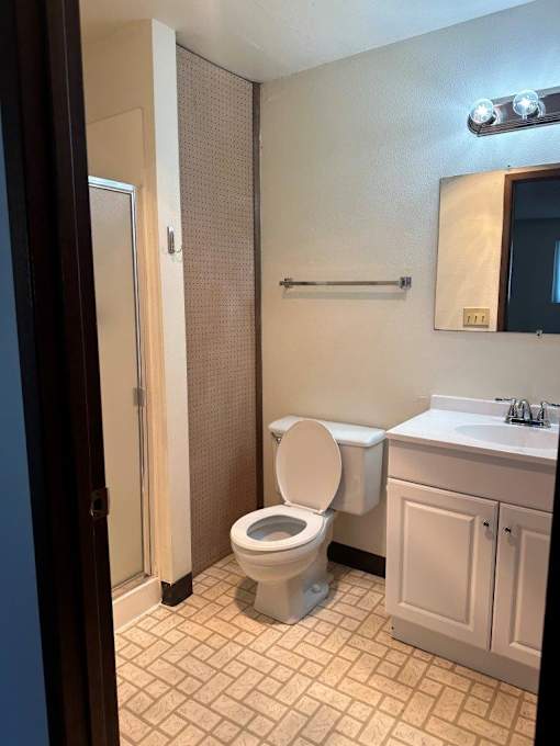 A white toilet sits in a bathroom next to a sink.