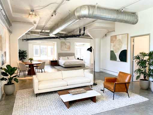 A living room with a white couch, a brown chair, and a white rug.