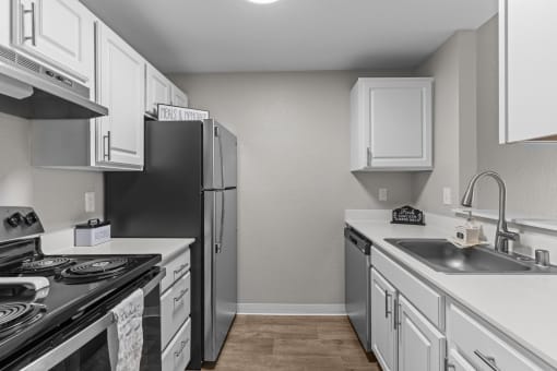 an empty kitchen with white cabinets and stainless steel appliances
