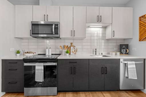 Gridline Apartments Kitchen with Stainless Steel Appliances and White Upper Cabinets and Gray Lower Cabinets