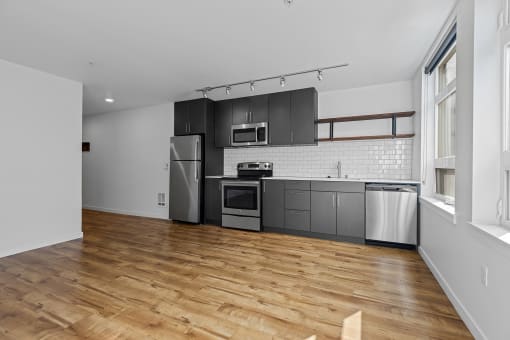 an empty kitchen with black cabinets and stainless steel appliances