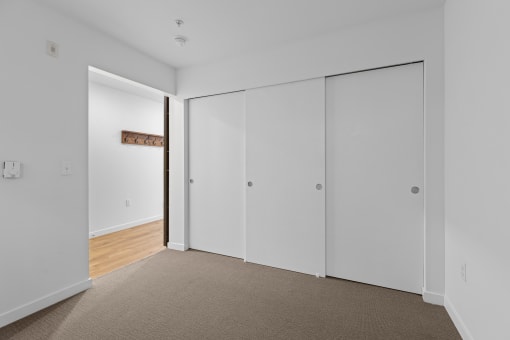 a bedroom with white walls and white closet doors