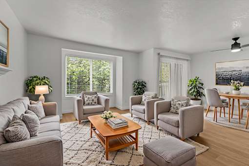 A living room with a grey couch, a coffee table, and a dining table.