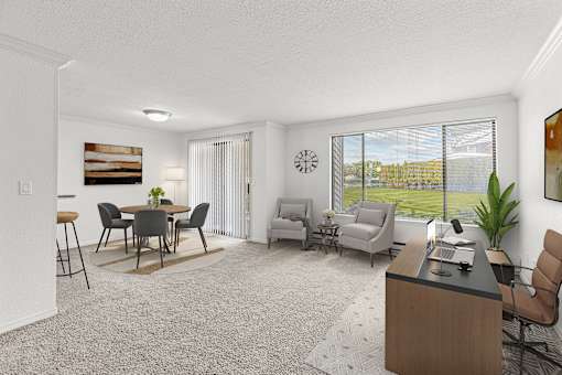 A living room with a dining table and chairs, a couch, a desk, and a large window with a view of the outdoors.